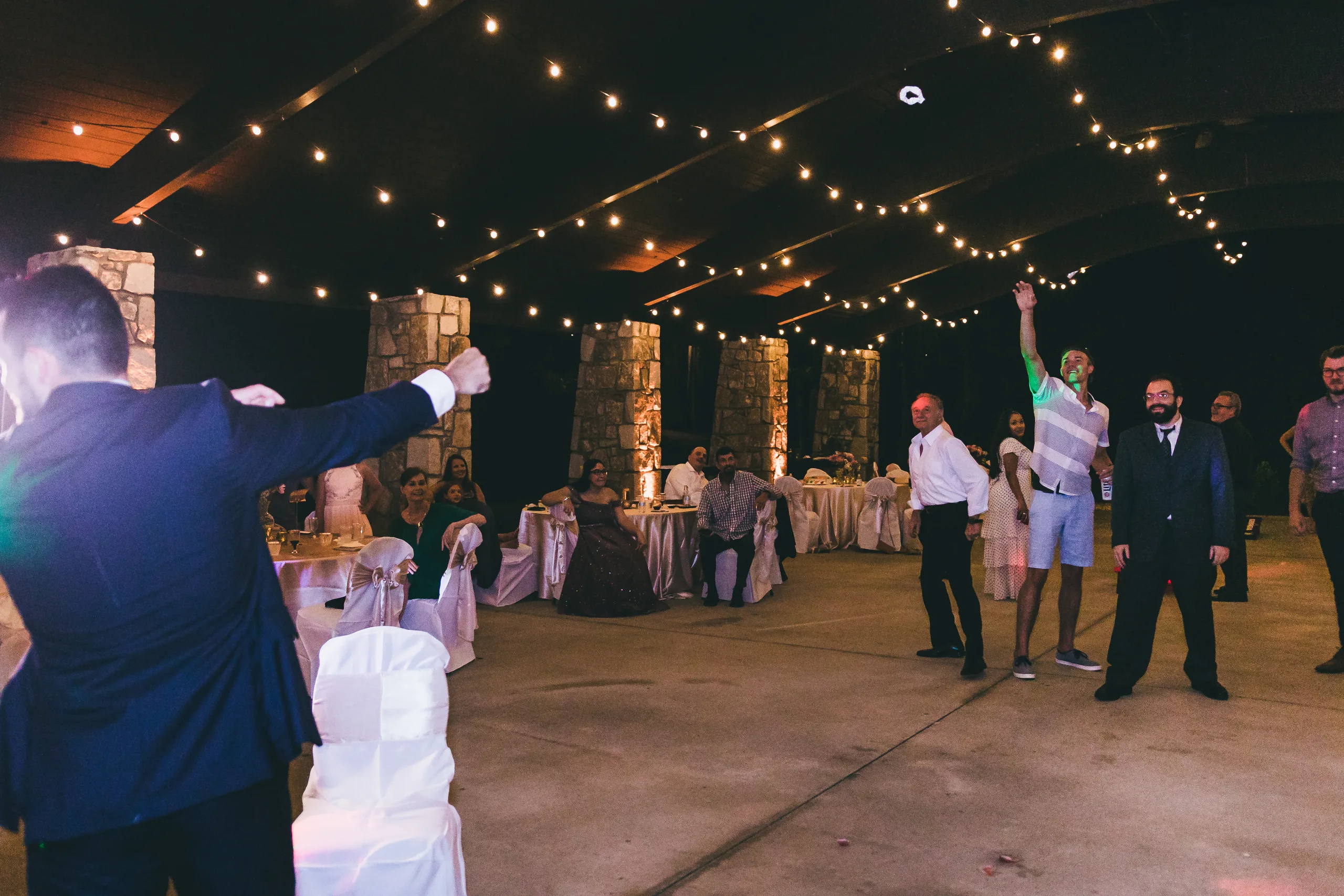 Reception: the groom tossing the garter, at their wedding at Atlanta Evergreen Lakeside Resort in Stone Mountain, GA