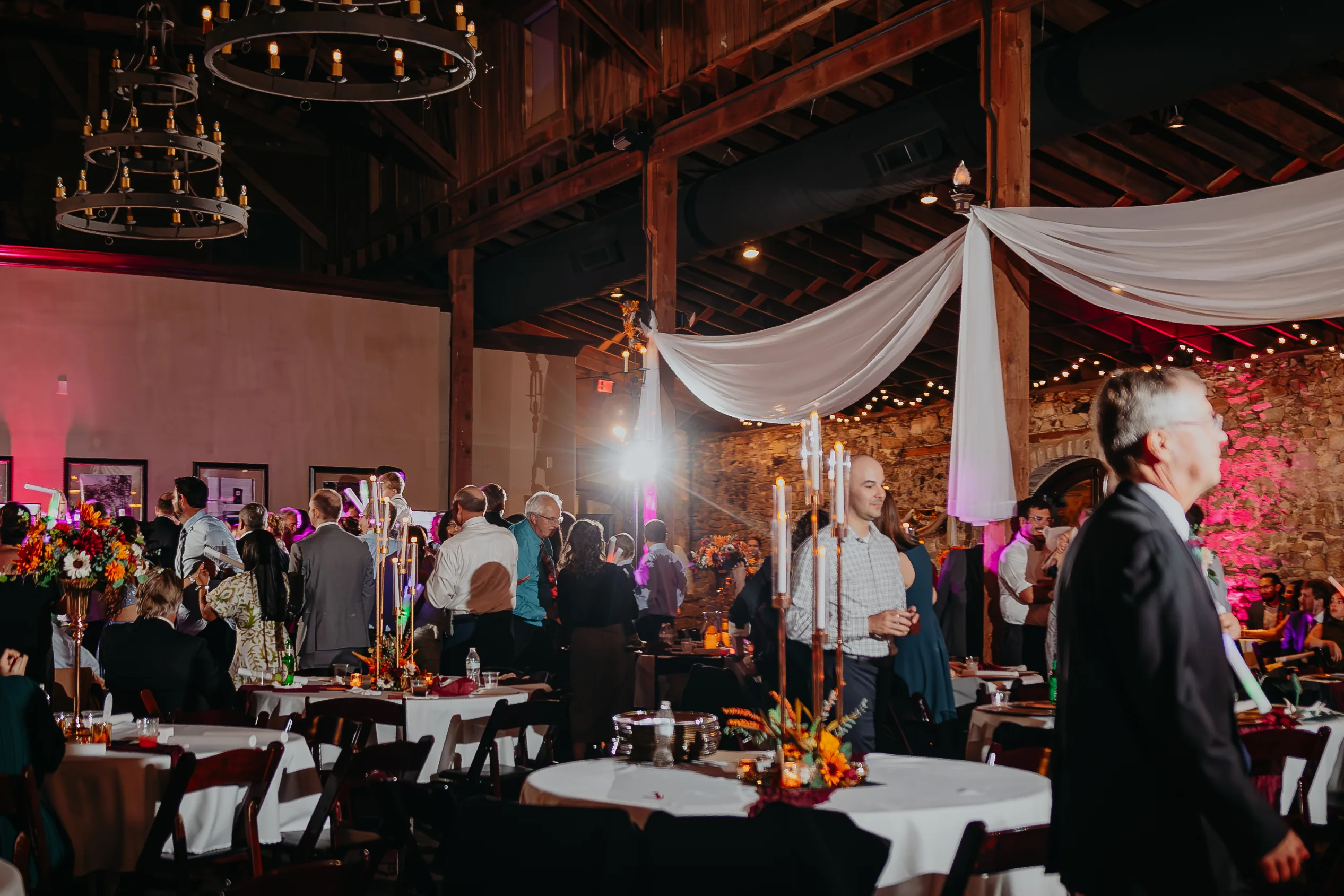 Reception: guests at the tables under the chandeliers, at their wedding at 550 Trackside in Lawrenceville, GA