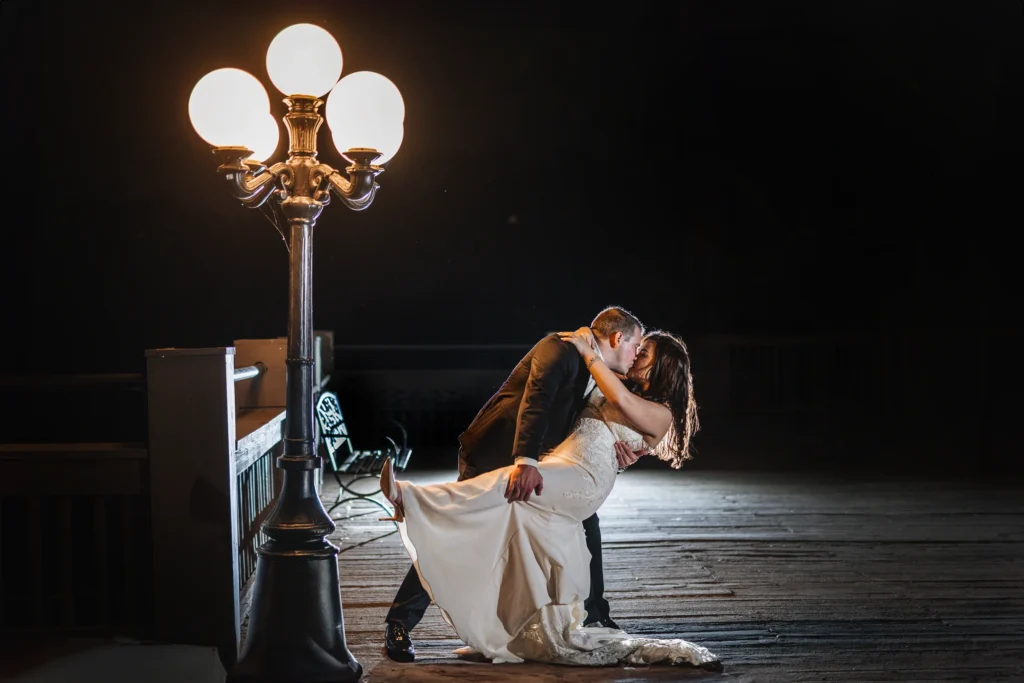 Wedding Formals: a dip kiss under the lamp post at night at their wedding at Ivy Hall at Roswell Mill in Roswell, GA
