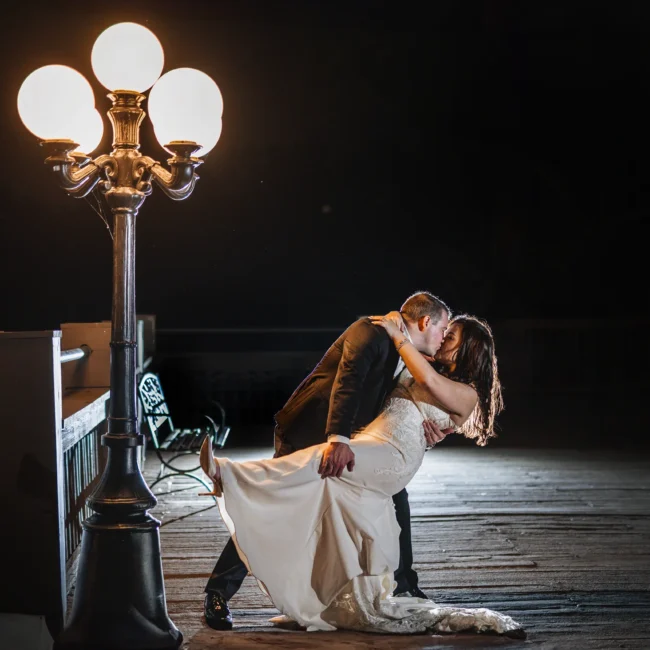 Wedding Formals: a dip kiss under the lamp post at night at their wedding at Ivy Hall at Roswell Mill in Roswell, GA