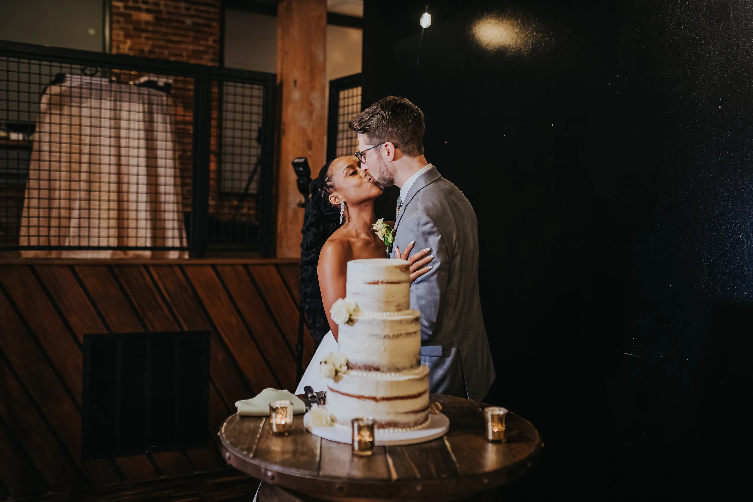 Reception: a kiss behind the cake, at their wedding at Terminus 330 in Atlanta, GA