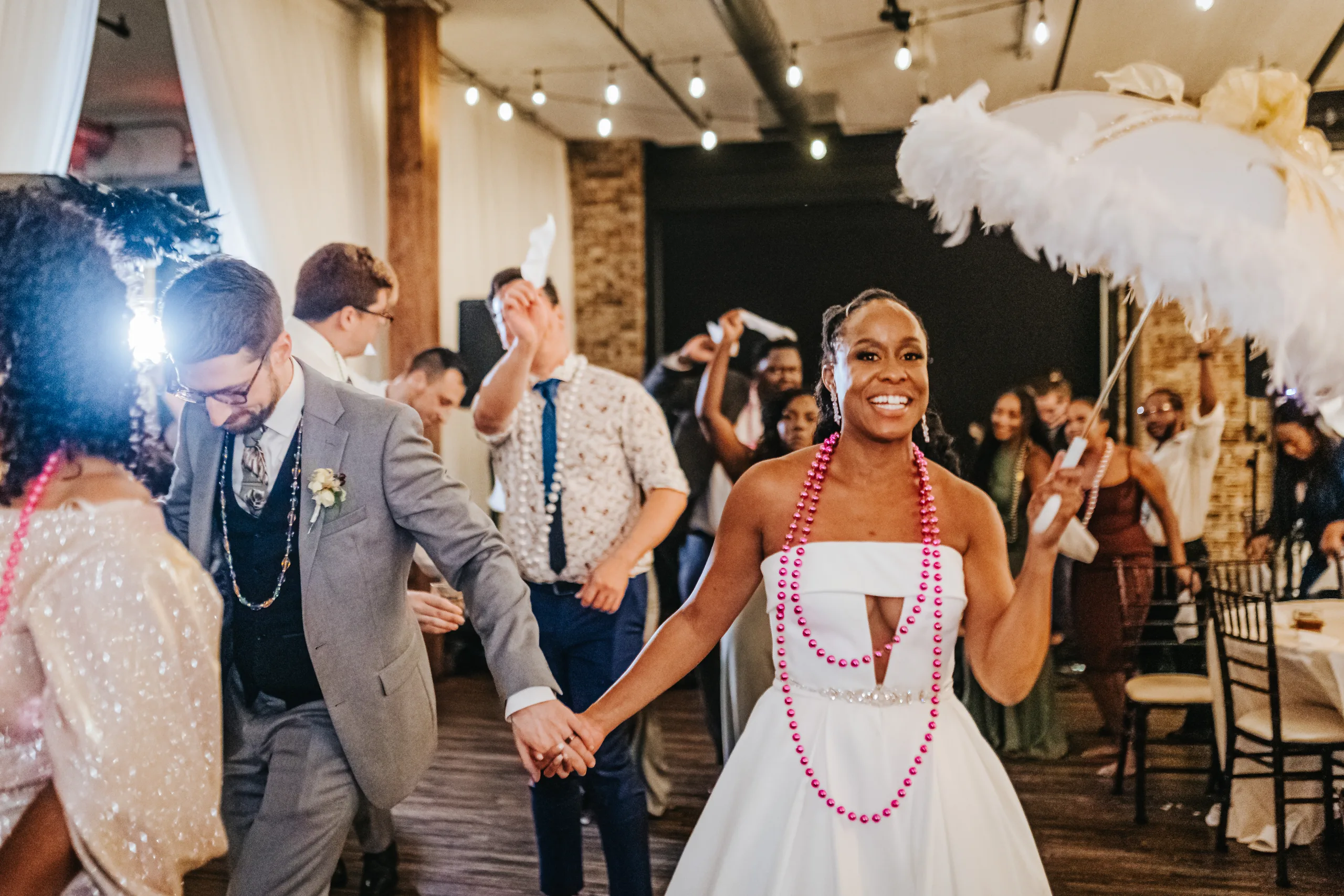 Reception: dancing with beads and a feather parasol in the second line, at their wedding at Terminus 330 in Atlanta, GA