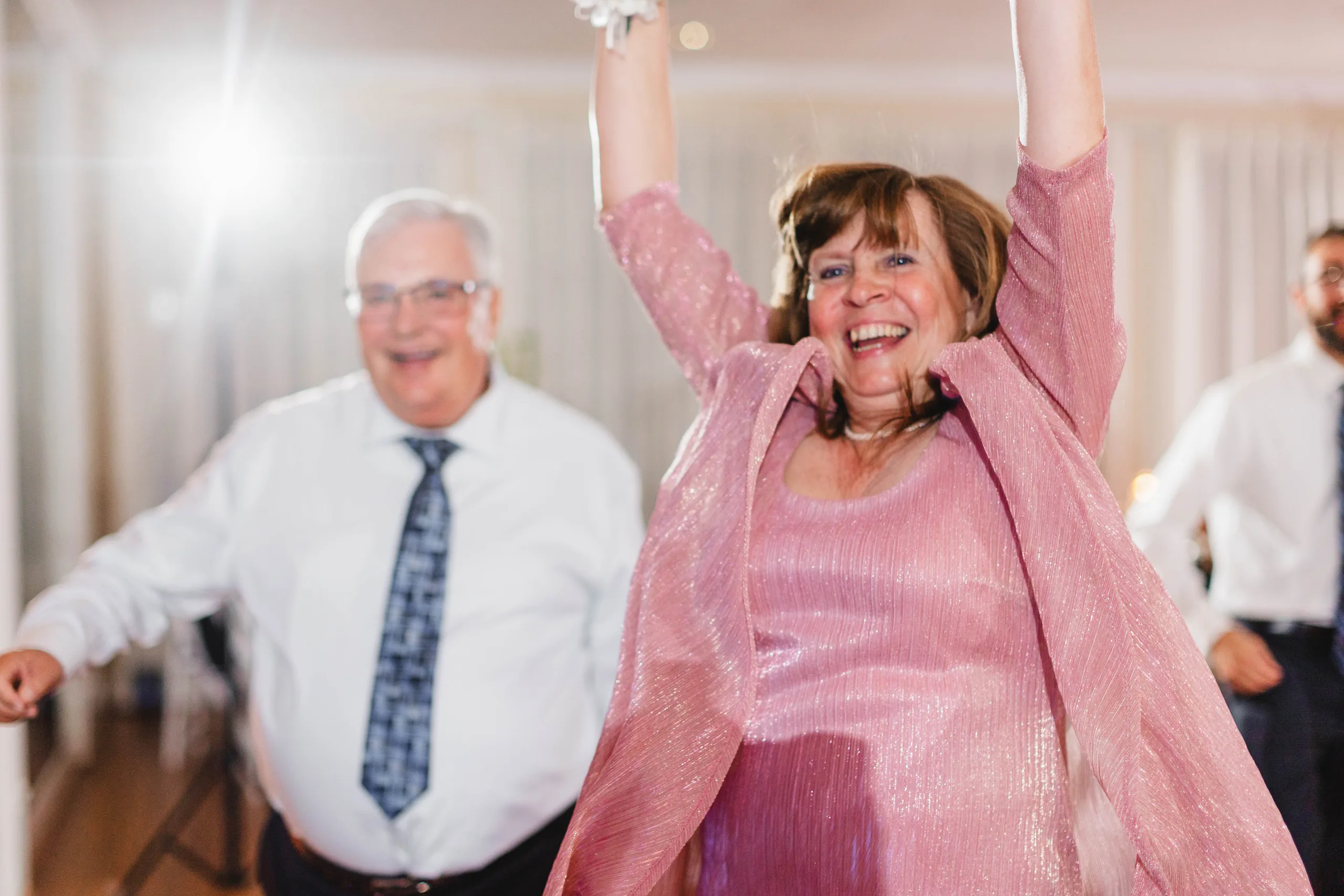 Reception: a guest with her arms up on the dance floor, at their wedding at Naylor Hall in Roswell, GA