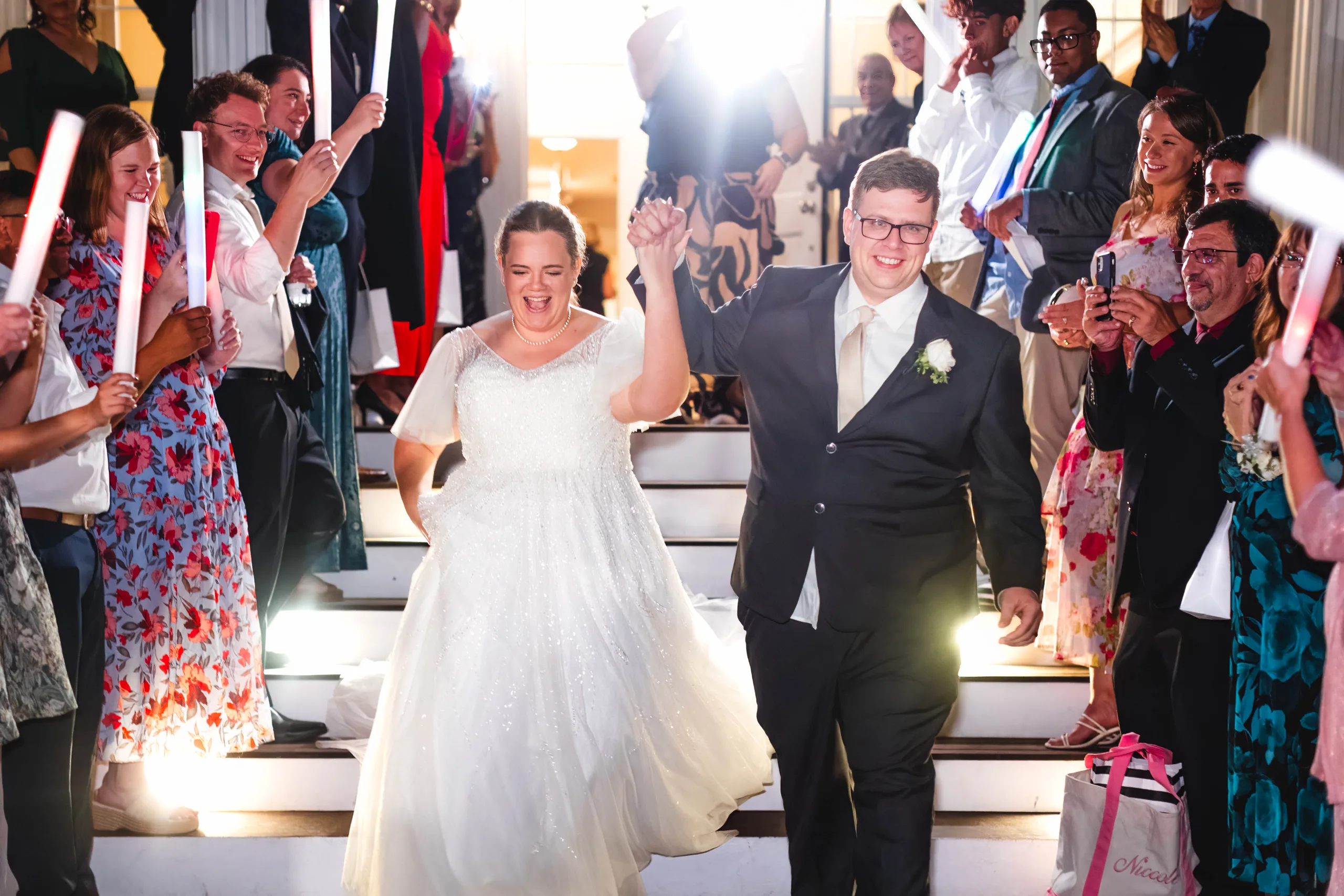 Send-Off: cheering through the light-up wands at the bottom of the steps, at their wedding at Naylor Hall in Roswell, GA