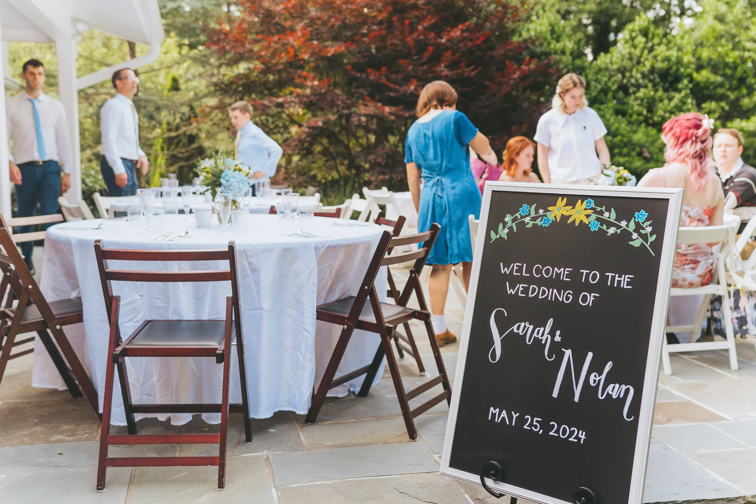 Reception Details: the welcome sign and tables on the patio, at their wedding reception at a family home