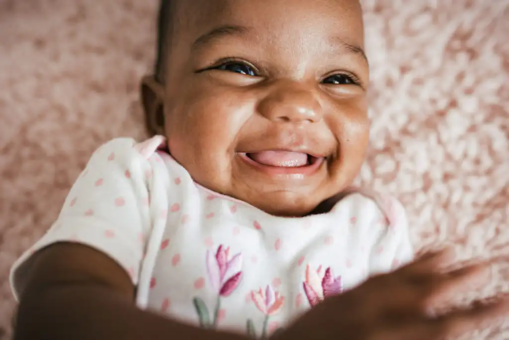 Laughing baby photographed on a pink blanket during a milestone portrait session