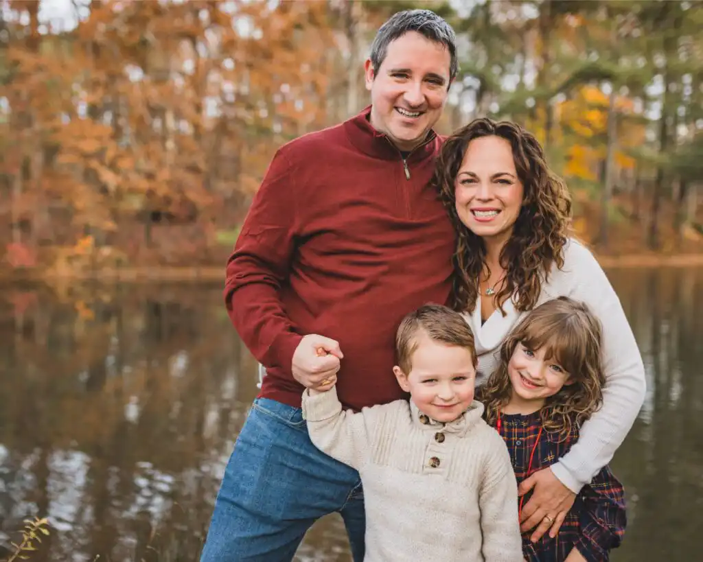 Family of four photographed beside a lake in autumn during a family portrait session